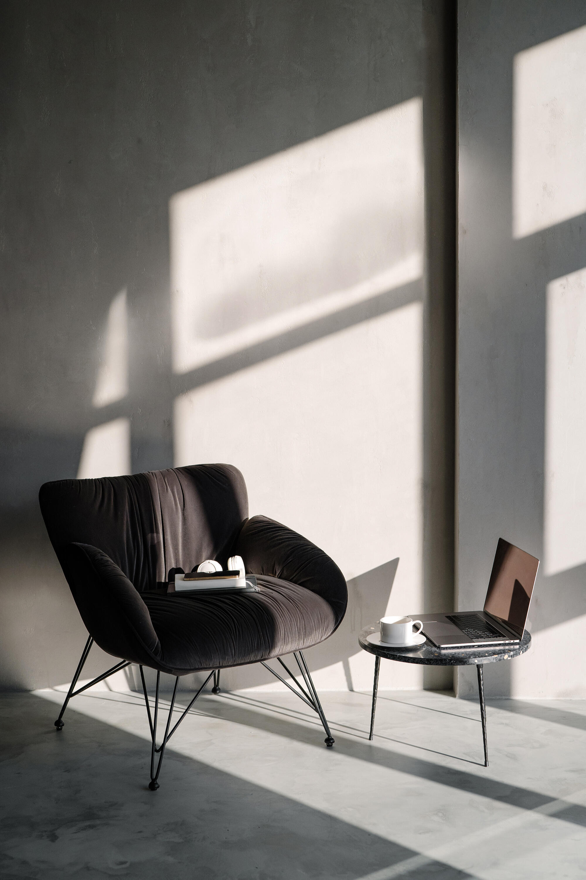 Pink Fruit Agency | LinkedIn Consultancy Black lounge chair beside a laptop in a minimalist sunlit workspace.